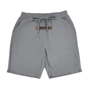 Detail view of breathable grey linen shorts featuring drawstring waist and logo patch