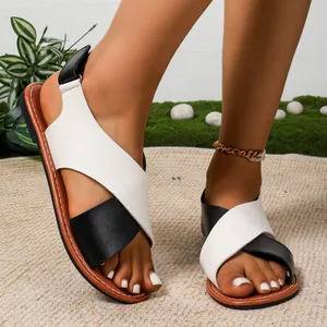 Detalle de sandalias planas con correas cruzadas blancas y negras.