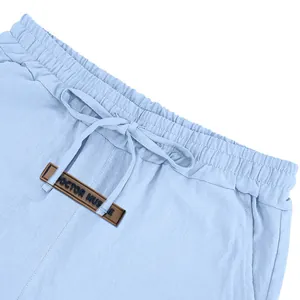 Detail view of light blue linen shorts waistband with drawstring and leather patch