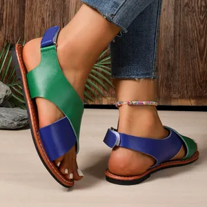 Primer plano de sandalias planas para mujer con tiras cruzadas en verde y azul.