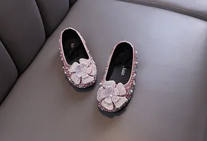 Detailed macro view of pink girl's princess shoes featuring sparkling rhinestone flowers.