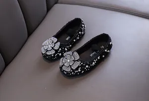 Close-up of elegant black girls' princess shoes with rhinestone flowers and pearls