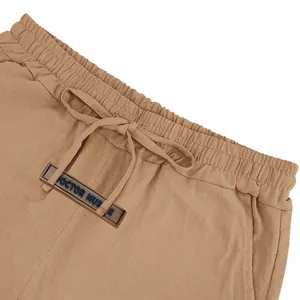 Detail of breathable khaki linen shorts with drawstring waist and logo patch.