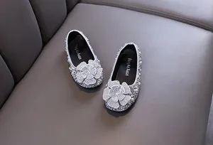 Detailed view of silver rhinestone princess shoes with large floral embellishment