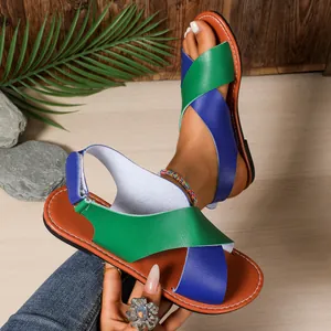 Detalle de sandalias planas con correas cruzadas verde y azul estilo playero