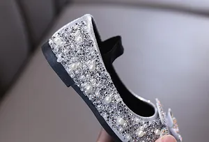 Close-up of sparkling rhinestones and pearls on silver girl's princess dress shoes