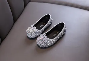 Close-up detail of sparkling silver girls' princess dress shoes with rhinestone flowers.