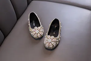 Close-up of sparkling girl's princess shoes with rhinestone flower and pearls.