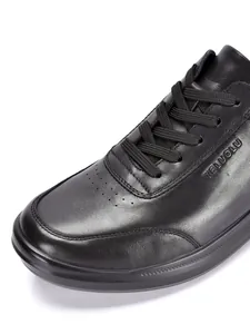 Primer plano de zapato casual para hombre en cuero negro con textura fina y logotipo.