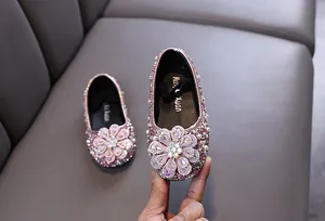 Macro view of pink girls princess shoes featuring a large sparkling rhinestone flower
