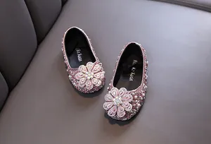 Close-up of pink sequin girl's flats featuring a large rhinestone flower ornament
