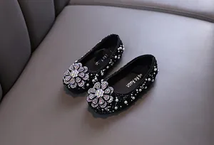 Detailed macro view of black girl's princess dress shoes featuring rhinestone flowers and pearls.
