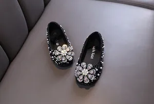 Close-up of sparkly black girls princess shoes with rhinestone flower and pearl trim