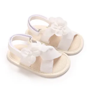 Détail de sandales blanches bébé fille avec fleurs en tissu et semelles souples antidérapantes