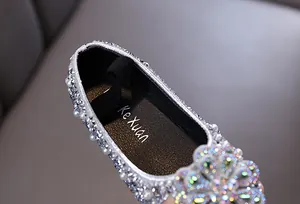 Close-up of sparkling rhinestones and pearls on silver girl's princess dance shoes