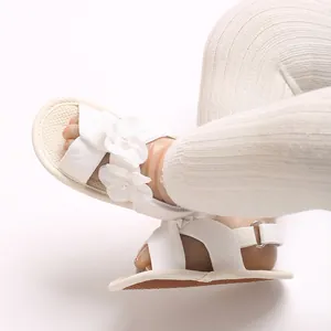 Détail de sandales blanches pour bébés filles avec perles florales et semelles souples.