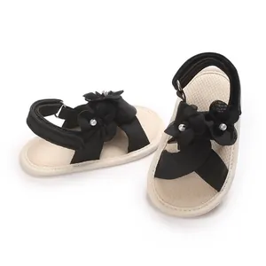 Détail rapproché de sandales d'été pour bébé fille avec fleurs noires et perles.