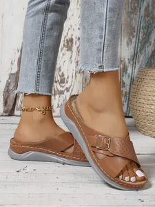 Close-up view of women's brown wedge sandals with stylish cross straps and metallic buckle