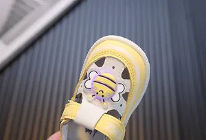 Close-up van een gele babysandaal met een schattig LED-verlicht cartoon bijendecoratie