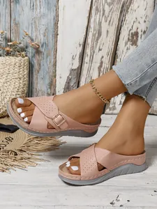 Detailed view of pink wedge sandals with criss-cross straps and buckle detail on a model.