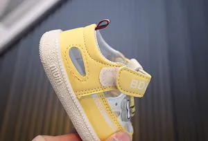 Close-up detail van gele babyzomersandalen met zachte zolen en verstelbare klittenbandsluiting
