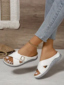 Detailed view of white cross-strap wedge sandals with buckle and punch-hole patterns.