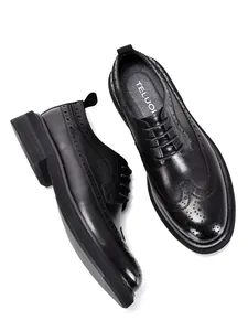 Overhead and side view of black leather brogue shoes with thick soles and wingtip details