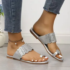 Close-up detail of women's silver toe-ring flat sandals with sparkling rhinestone decor