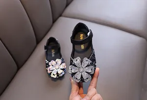 Close-up detail of girl's princess dress shoes featuring a large sparkling rhinestone flower
