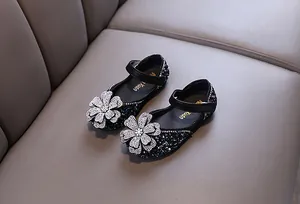 Detail view of sparkling rhinestone flower on girls' black princess Mary Jane shoes.