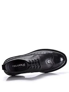 Detail view of black leather brogue shoes with intricate wingtip perforation and laces