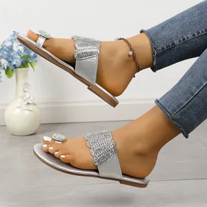 Detailed view of silver toe-loop flat sandals with sparkling rhinestone embellishments