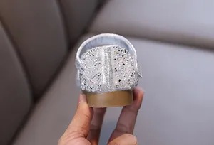 Close-up detail of silver rhinestone and pearl decorations on a girl's princess shoe heel.