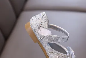 Close-up of girl's silver princess shoe with sparkling rhinestones and pearl details.