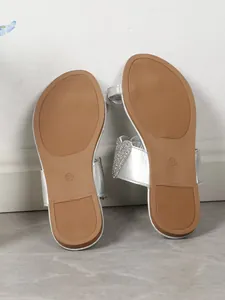Detail view of the non-slip rubber outsole on silver toe-loop flat sandals.