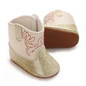 Detailweergave van beige babyboots met gouden glitters en rode geborduurde bloemendetails