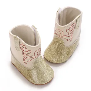 Detailopname van crème babyboots met gouden glitters en rood borduurwerk