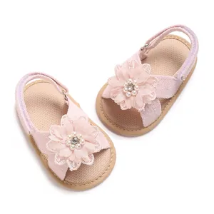 Detail shot of pink baby sandals with large floral pearl ornaments and soft soles.