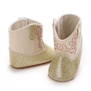 Detail van beige baby-wandelschoenen met gouden glitters en rood geborduurd patroon