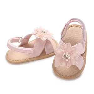 Close-up detail of pink baby girl sandals featuring large flower and pearl accents