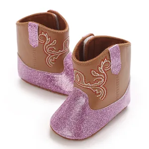 Detailopname van babymeisjes cowboylaarzen met roze glitter en bloemige borduurpatronen