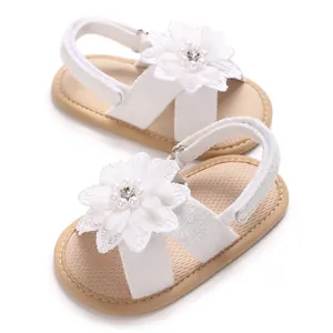 Detailed view of white baby sandals with decorative pearl and rhinestone flower