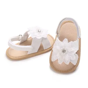 Close-up of white baby girl sandals showing the large flower decoration and pearl