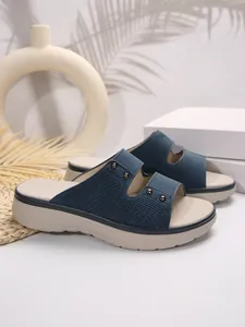Close-up detail of navy blue platform slides featuring textured straps and metal studs.