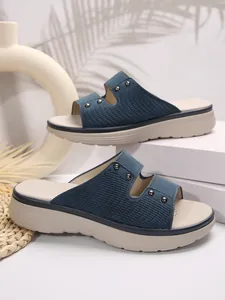 Close-up detail of women's stylish blue textured platform slides with metallic studs
