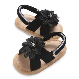 Macro view of black baby girl sandals featuring a delicate flower decoration and soft sole