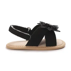 Side view detail of baby girl black sandal with delicate lace flower and soft sole.