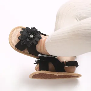 Close-up of baby girl's black sandals featuring a large fabric flower with pearls