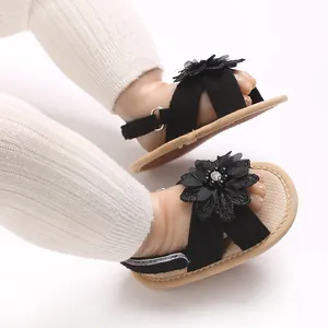 Close-up detail of black baby sandals with cute floral decoration and flexible soft soles