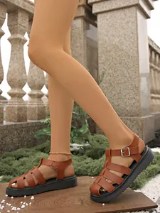 Stylische braune gewebte geschlossene Römersandalen mit dicker schwarzer Sohle im Freien.